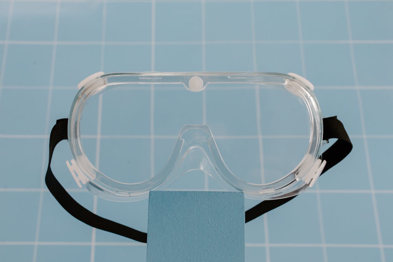 Clear protective goggles resting on a blue surface, ideal for safety and lab use.